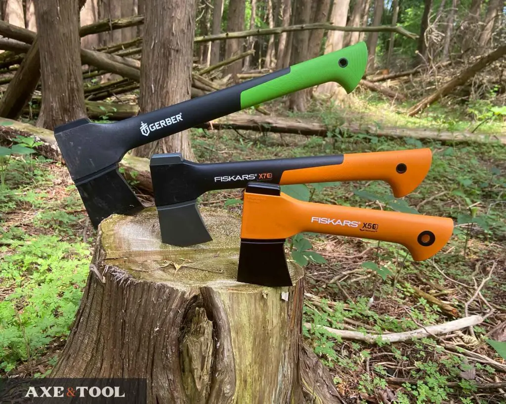 three fiskars and gerber hatchets in a log in the woods