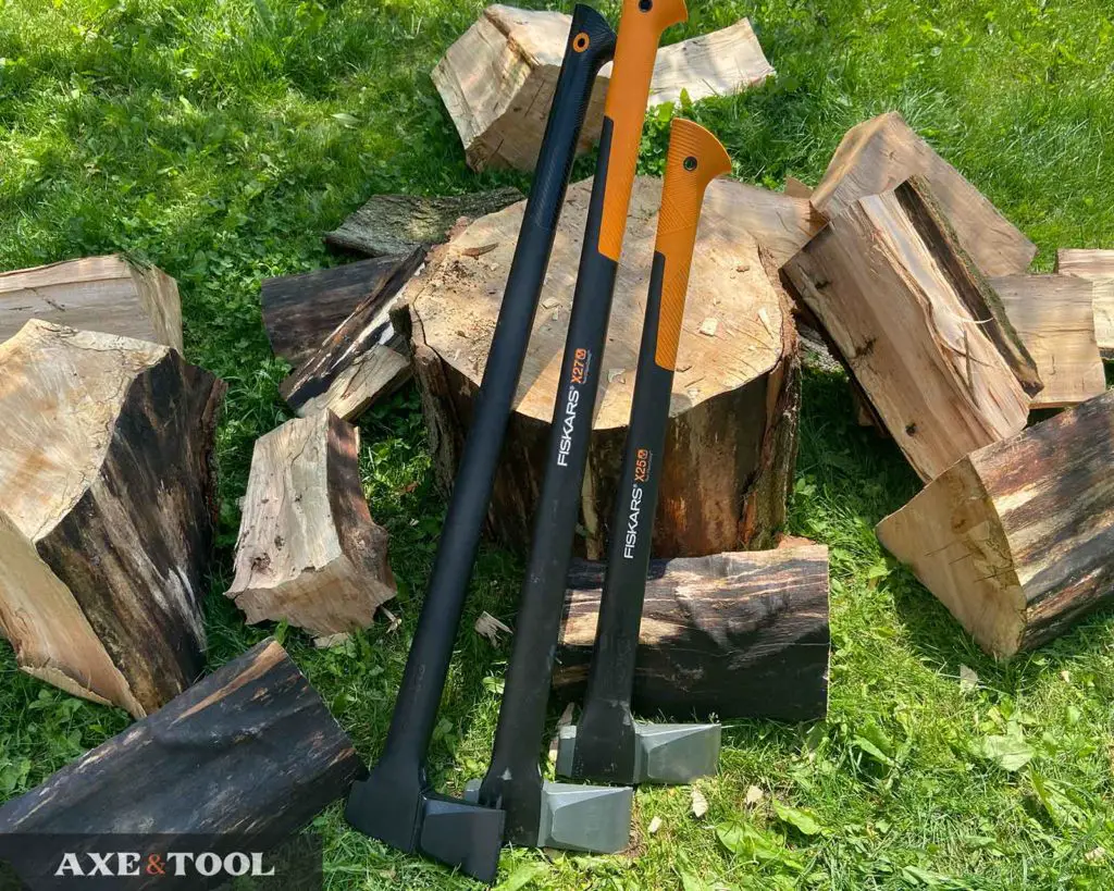 Three large Fiskars splitting axes on a pile of wood